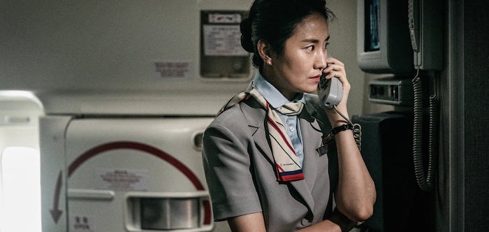 L'hôtesse de l'air garde son calme alors que le virus commence à infecter les passagers de l'avion dans le film Défense d’atterrir de Han Jae-rim